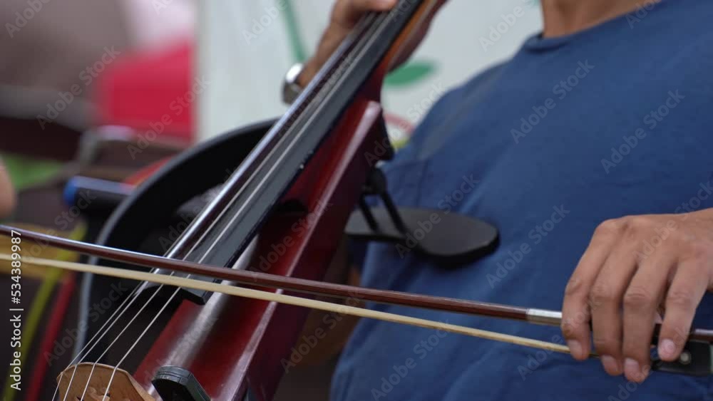 Close up of Man hand playing cello. Man musician playing the violoncello. Cello player playing cello bow outdoor Close up of Man hand playing cello. Man musician playing the violoncello. Cello player playing cello bow outdoor