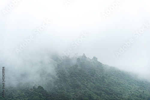 Mountain range with visible silhouettes through the morning colorful fog. © panyawatt