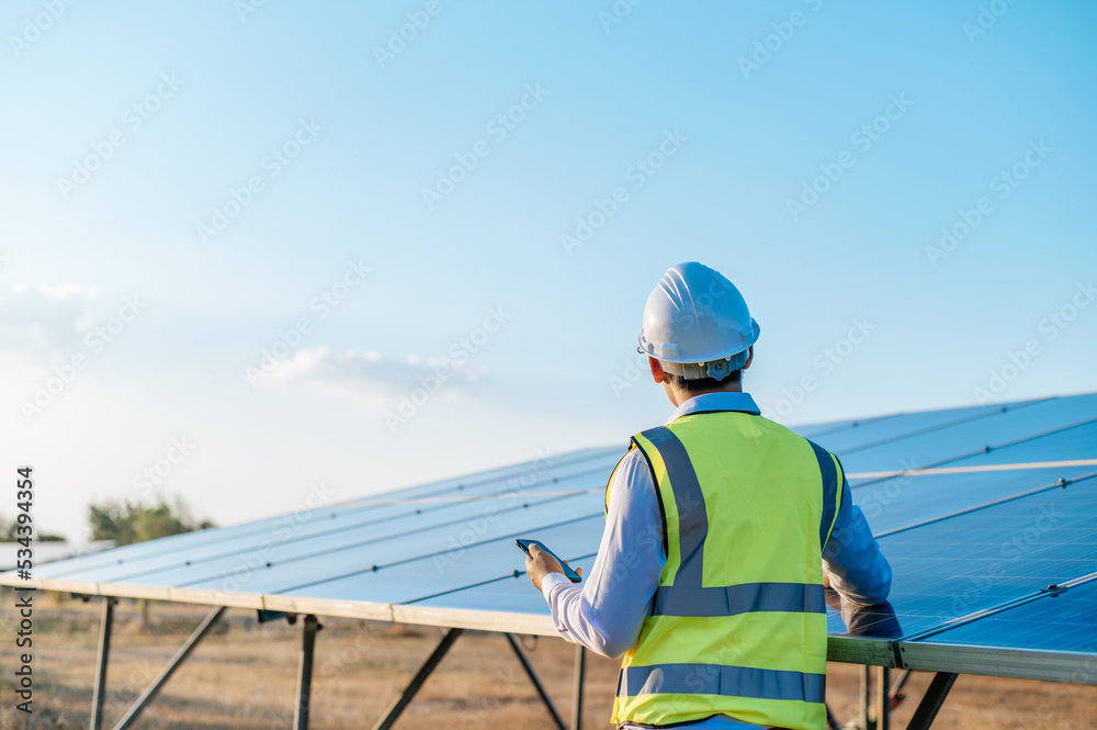 Young engineer use smartphone while working at solar farm Young engineer use smartphone while working at solar farm