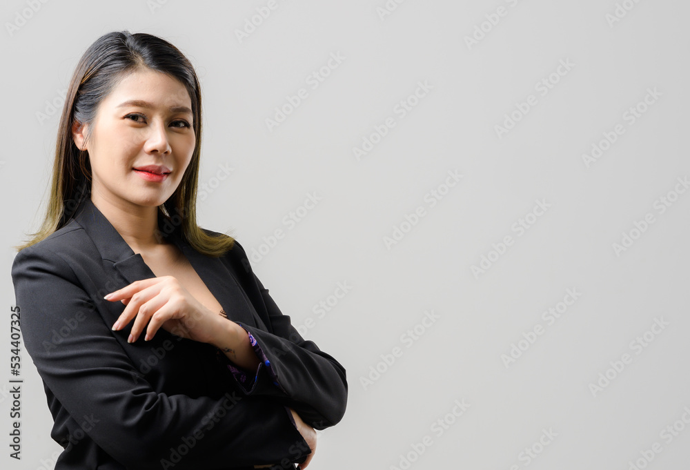 Smiling asian business woman pointing up and looking at the camera over gray background Smiling asian business woman pointing up and looking at the camera over gray background