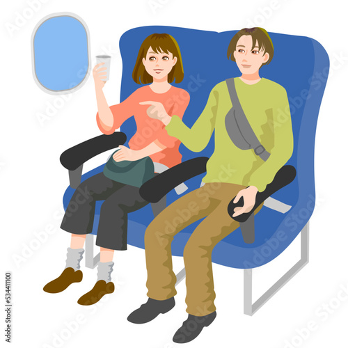 機内の窓から外を見る若い男性と女性、女性は手に飲み物を持っており、男性は窓の外を指差している