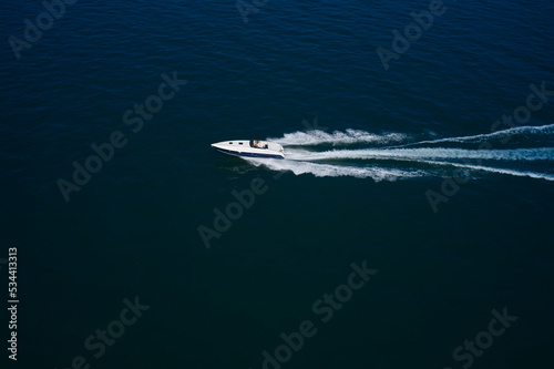 Luxurious Blue boat motorboat rushes through the waves of the blue Sea. Boat fast moving aerial view. Luxurious boat fast movement on dark water. © Berg