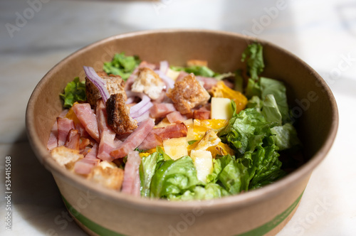 Caesar salad in a cardboard plate, healthy proper nutrition, recyclable waste.