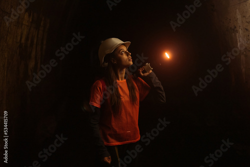 Female digger with flashlight explores the tunnel