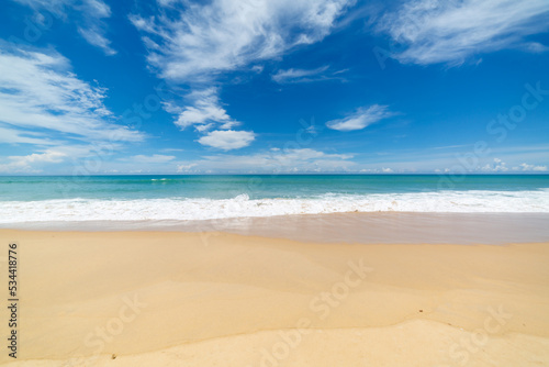 scenery smooth waves from green sea hit on the white long beach..beautiful nature on the beach..white cloud in blue sky background..