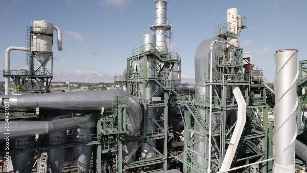 Large wood processing factory, view of the steel pipes and tanks from height, industrial structure of the plant, smoke coming from the pipes. Large wood processing factory, view of the steel pipes and tanks from height, industrial structure of the plant, smoke coming from the pipes.