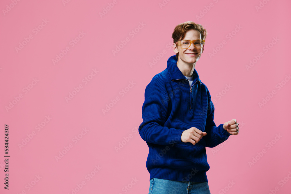 a joyful, happy, funny guy stands on a pink background dancing happily in orange glasses and a blue autumn zipper sweater. test space a joyful, happy, funny guy stands on a pink background dancing happily in orange glasses and a blue autumn zipper sweater. test space