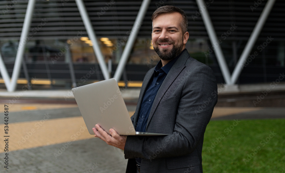 male business analyst with a laptop on the background of an office building male business analyst with a laptop on the background of an office building