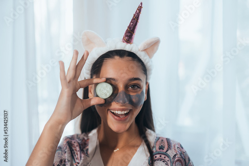 Funny smiling Spa Woman with fresh Facial Mask hold cucumber.