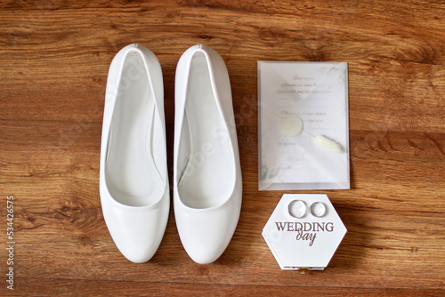 Wedding rings, invitations and shoes of the bride on a wooden background. Preparation for the wedding. Wedding celebration.