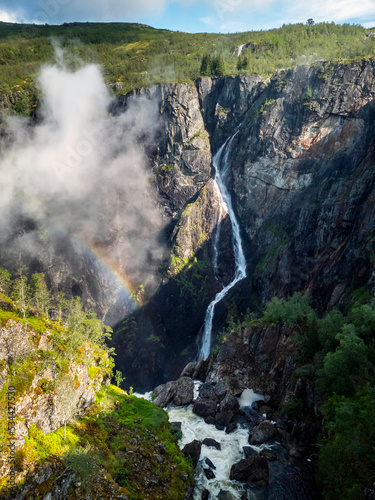 Amazing landscape with rainbow and low white clouds above a waterfall in the norwegian fjords, in southern Norway, Europe