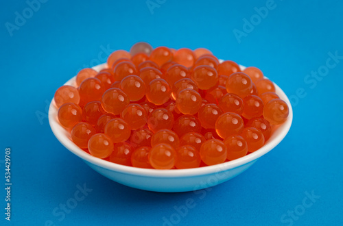 Bowl of Popping Boba Pearls on a Bright Blue Background