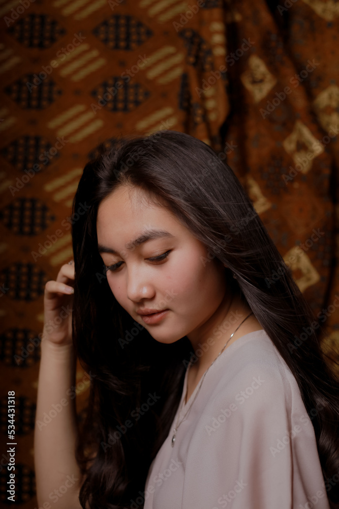 Beauty portrait of happy Asian woman face with natural skin on Indonesian Batik background.