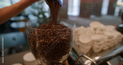 man poring coffee beans in a coffee grinder photo