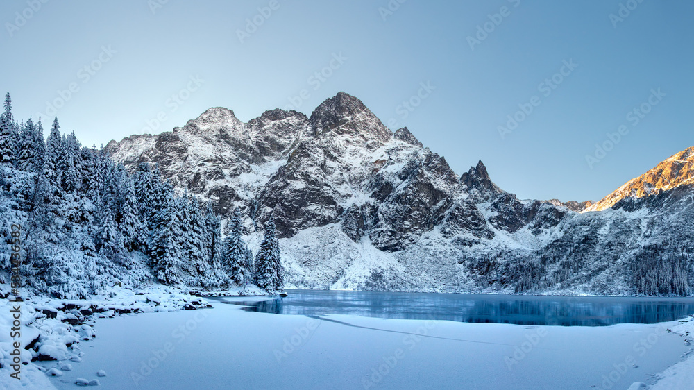 Winter landscape of frozen lake and covered snow trees in Tatra Mountains, Zakopane, Poland. Winter natural background. Beautiful winter sunrise in mountains.  