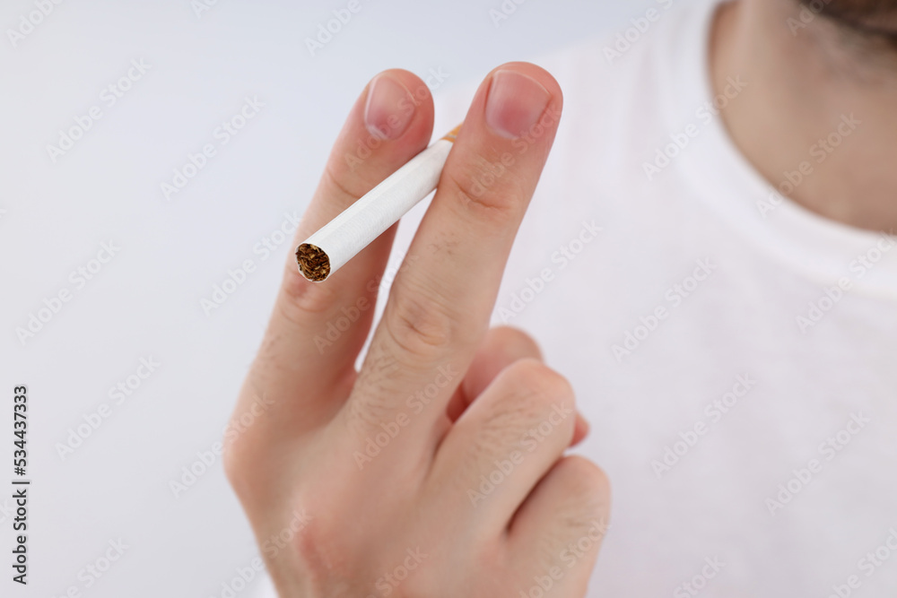 Man in white t-shirt holds cigarette, close up Man in white t-shirt holds cigarette, close up