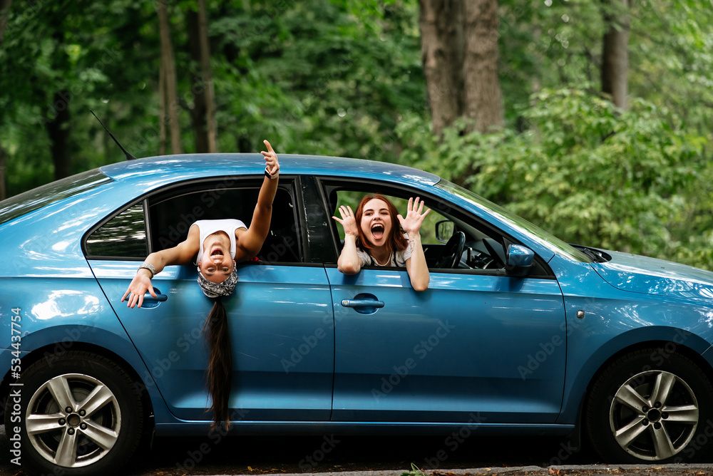 Two girlfriends fool around and laughing together in a car Two girlfriends fool around and laughing together in a car