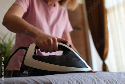 Woman ironing clothes on board at home closeup
