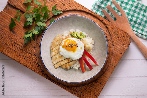 Teriyaki chicken donburi with fried egg, onion, red pepper and other vegetables. Typical Japanese dish.