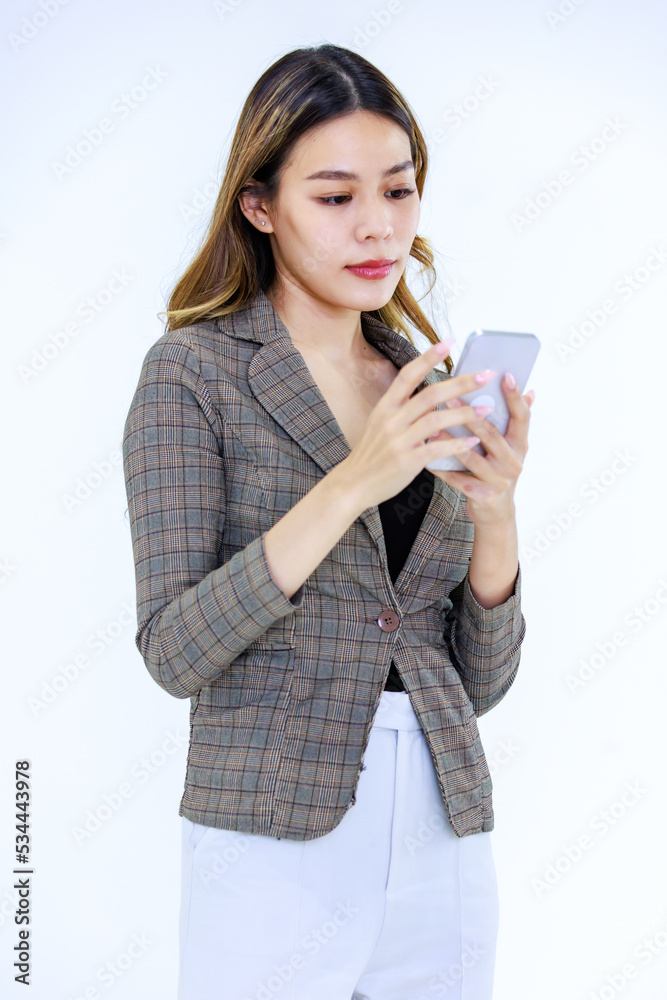 Isolated cutout studio shot Millennial Asian successful professional female businesswoman in formal suit standing smiling posing holding mobile phone on white background Isolated cutout studio shot Millennial Asian successful professional female businesswoman in formal suit standing smiling posing holding mobile phone on white background