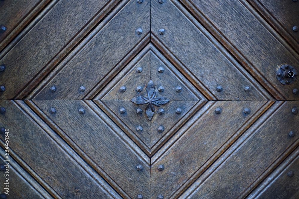 Detail of an old wooden door with traditional metal door knob.