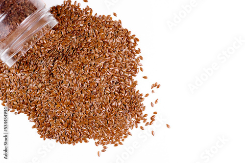 Flax seeds spill out of the jar. Isolate on a white background. View from above. Place for text