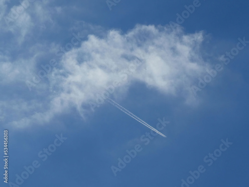 Contrail of smoke from jet engine of the airplane over the blue sky from the cloud