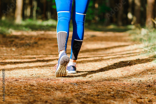 Female runner jogging outdoors through a summer forest trail.Close up.Copy space.