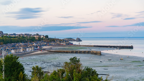Landscape view of the village of Cancale, Brittany, France, during low tide at dusk, with elegant historical buildings. Atlantic ocean on the background.