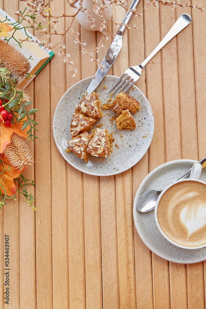 Aesthetic breakfast outside - cutting doughnut among fall decorations. Cappuccino in white ceramic cup on wooden table among flowers. Lunch coffee time. Aesthetic breakfast outside - cutting doughnut among fall decorations. Cappuccino in white ceramic cup on wooden table among flowers. Lunch coffee time.