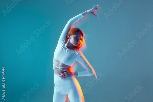 Fototapeta Naklejka Na Ścianę i Meble -  A beautiful athletic girl does bends. Isolated figures of a fitness model in a white sports uniform on a blue background.