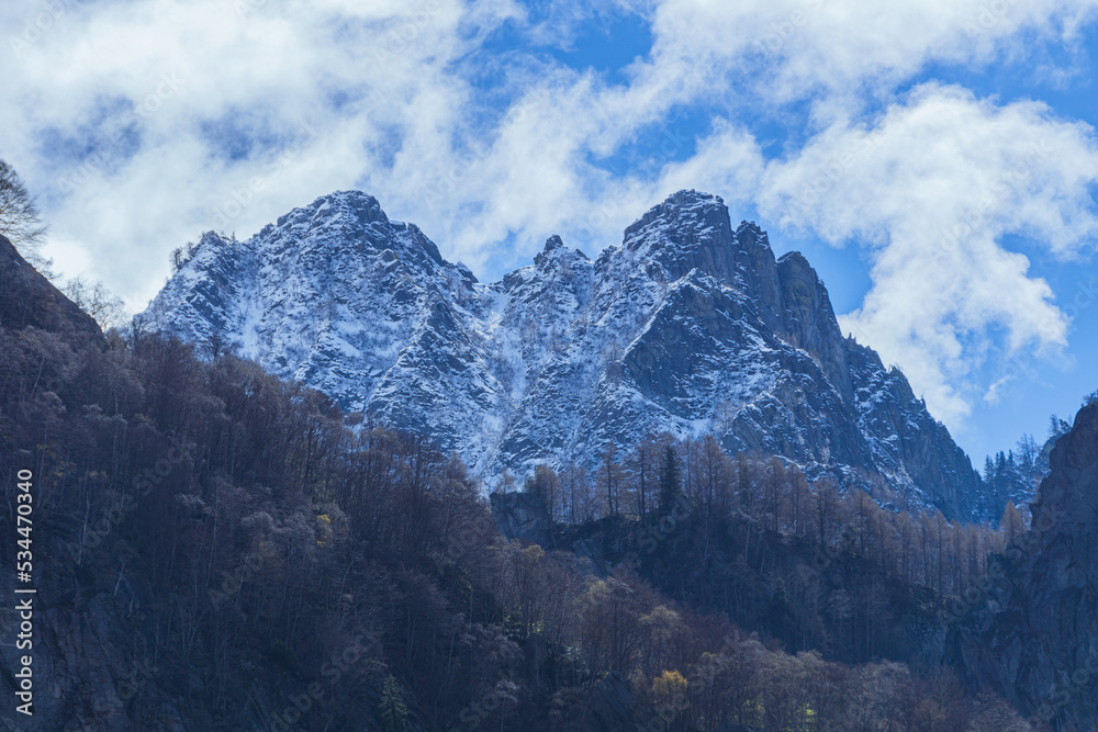 the mountains of val masino and val di mello with fresh snow, during a sunny day, near the town of San Martino, Italy - April 2022.