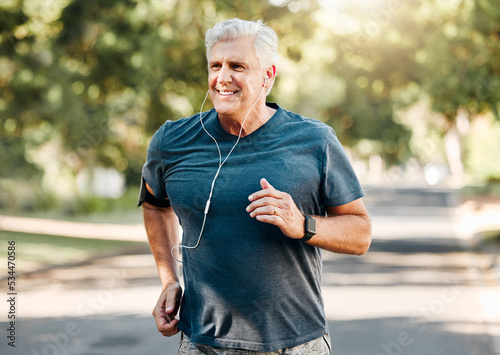 Senior man running while listening to music outdoor street and park for fitness, wellness or healthy lifestyle with summer lens flare bokeh. Elderly person exercise, workout or jogging with earphones