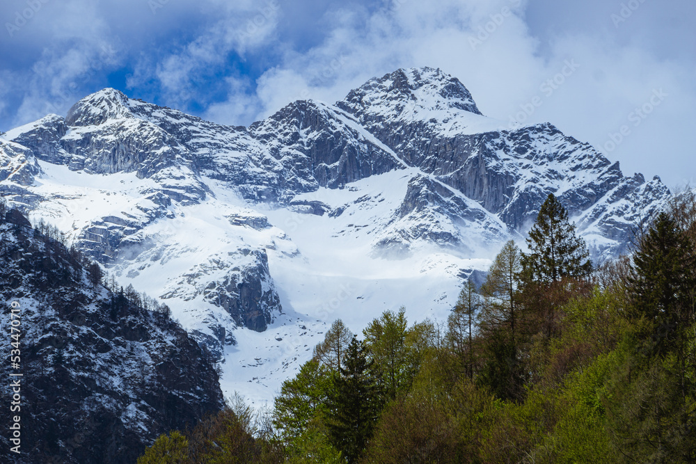 the mountains of val masino and val di mello with fresh snow, during a sunny day, near the town of San Martino, Italy - April 2022.