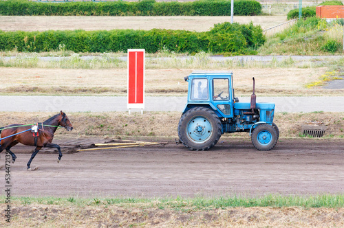 An old tractor is leveling a dirt treadmill for horses.