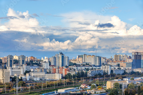 Cityscape, embossed white and gray clouds over dense urban areas on an autumn day.