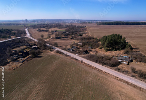 Road through the countryside, top view. A dirt road through an agricultural field, here from a drone. Field and road in middle, texture background. Rural landscape with arable land. Highway at field.