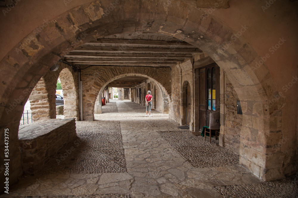 Touriste solitaire promenant sous les arcades du villde de sauveterre de Rouergue