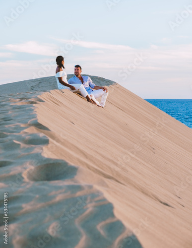 A couple walking at the beach of Maspalomas Gran Canaria Spain, men and woman at the sand dunes desert of Maspalomas Gran Canaria during vacation in Spain photo