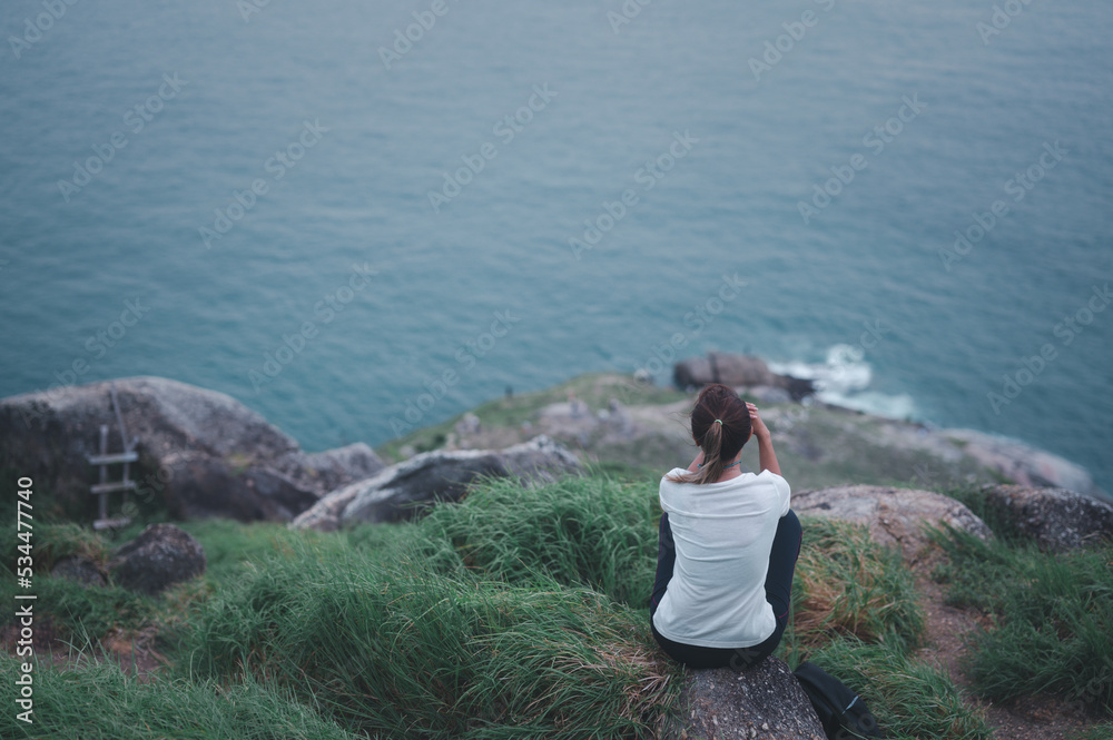 Young Asian woman runner sitting to relax on top of the mountain with beautiful views. Enjoying freedom in life. Young Asian woman runner sitting to relax on top of the mountain with beautiful views. Enjoying freedom in life.