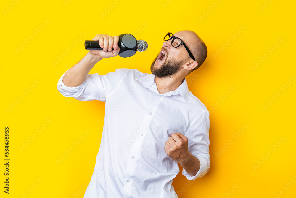 Singing young man with closed eyes with a microphone on a yellow background Singing young man with closed eyes with a microphone on a yellow background
