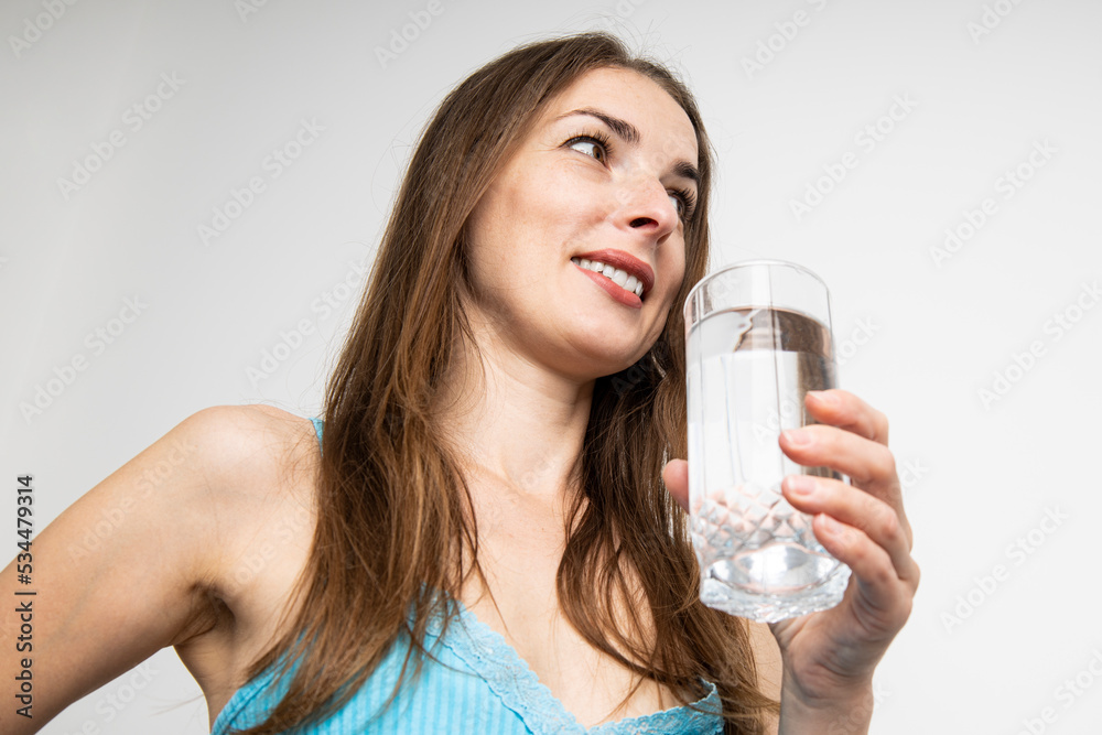 Smiling young woman holding a glass of water on a white background. Top view, flat lay Smiling young woman holding a glass of water on a white background. Top view, flat lay