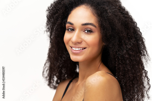 Portrait view of the beautiful multiracial woman with naked shoulders smiling while standing at the isolated white background. Stock photo