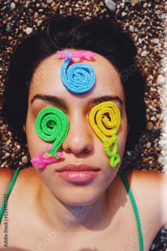 closeup of young woman with childrens toys on face at summer day