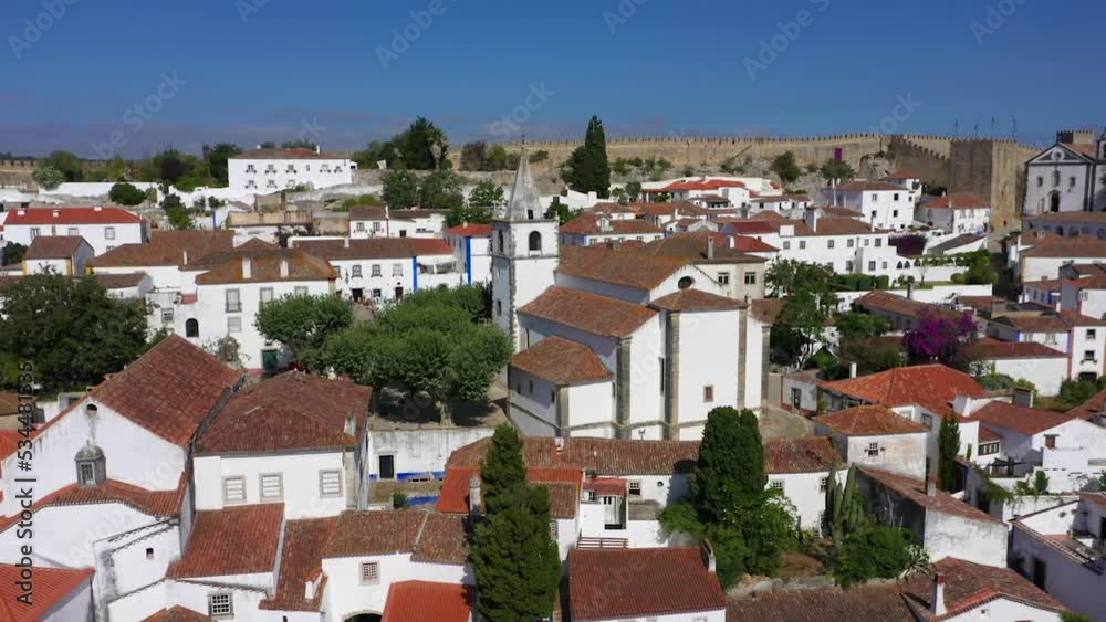 Aerial view away from the Igreja de Santa Maria church in Obidos town in sunny Oeste, Portugal - rotating, pull back, drone shot Aerial view away from the Igreja de Santa Maria church in Obidos town in sunny Oeste, Portugal - rotating, pull back, drone shot