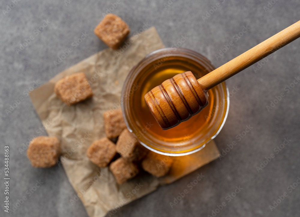 Brown sugar with honey and wooden honey dipper on stone background. Brown sugar with honey and wooden honey dipper on stone background.