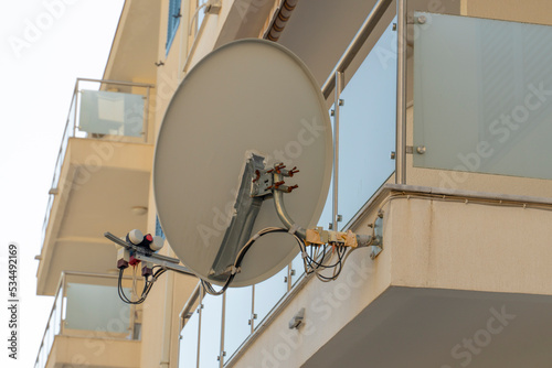 TV dish on the balcony Denmark. A TV dish connected by wires transmits information via satellite. Satellite Dish. Television photo