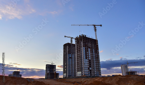 Сonstruction site with tower cranes on building construction. Builder on formworks. Cranes on pouring concrete in formwork. Tower cranes on construction. Built environment. Buildings renovation..