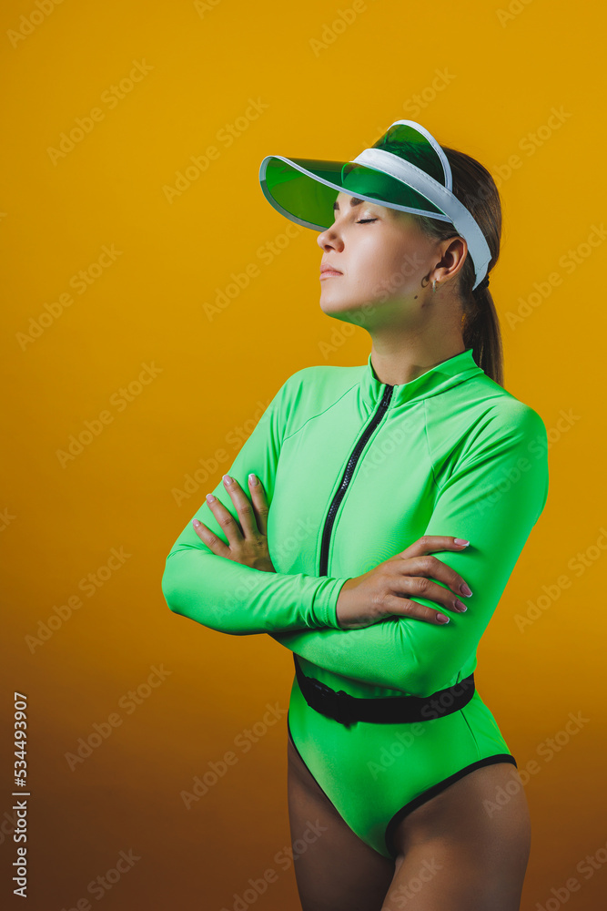 Attractive woman in bright green beach swimsuit, hat, on bright yellow background with perfect body. Isolated. Studio shot. Attractive woman in bright green beach swimsuit, hat, on bright yellow background with perfect body. Isolated. Studio shot.