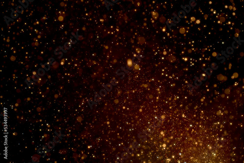 Natural organic golden dust particles floating on black background. Glittering sparkling flickering glowing.